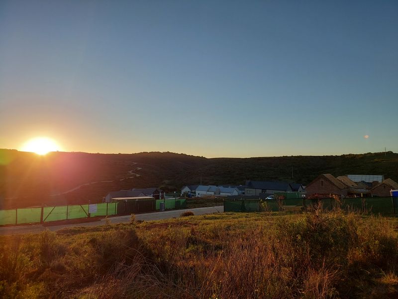 A scenic view of the surrounding landscape and hills at sunset, overlooking a residential development area.