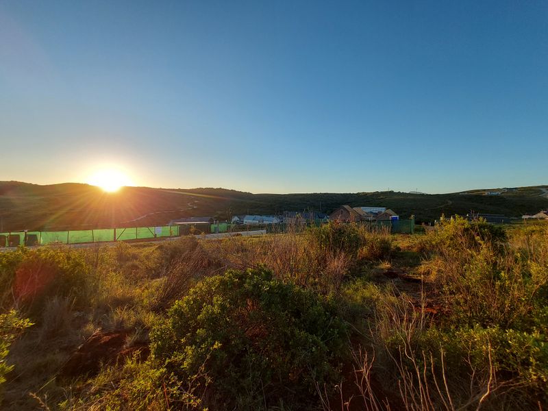 A scenic landscape view of the surrounding hills and horizon at sunset, showcasing the natural environment and local terrain.