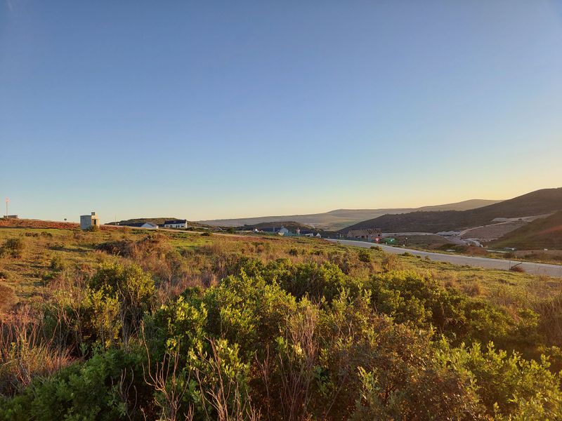 A scenic view of the surrounding landscape featuring natural vegetation, rolling hills, and a paved road leading through the area.
