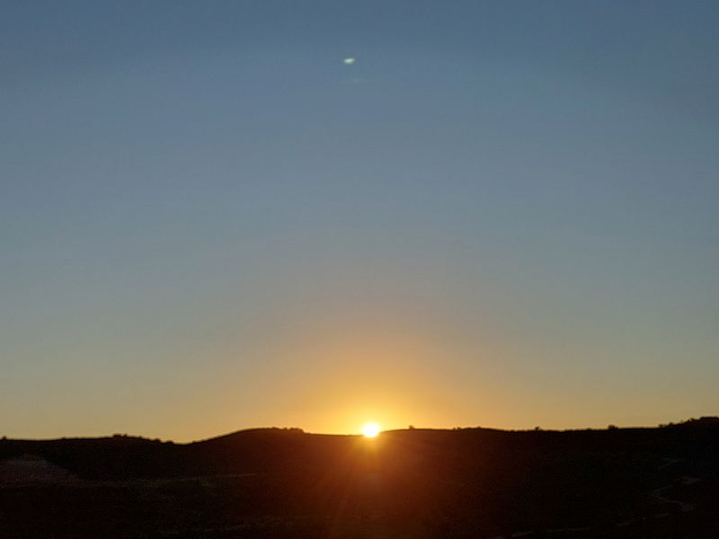 A scenic view of the horizon at sunrise over rolling hills.