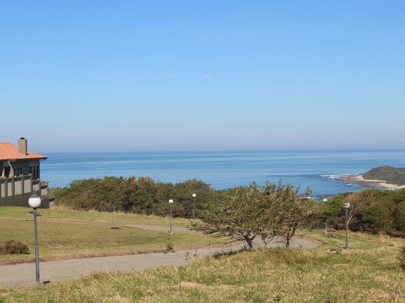 A scenic view of the coastline and ocean from the residential land, featuring paved pathways and established landscaping.