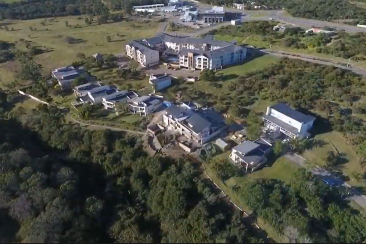 Aerial view of a residential estate featuring multiple detached homes and a larger apartment complex set within a natural landscape.