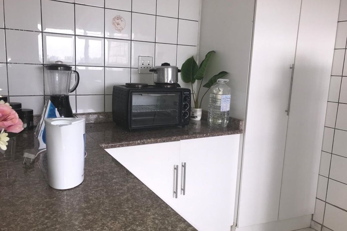 A functional kitchen area featuring granite countertops, white cabinetry, and tiled wall splashbacks.