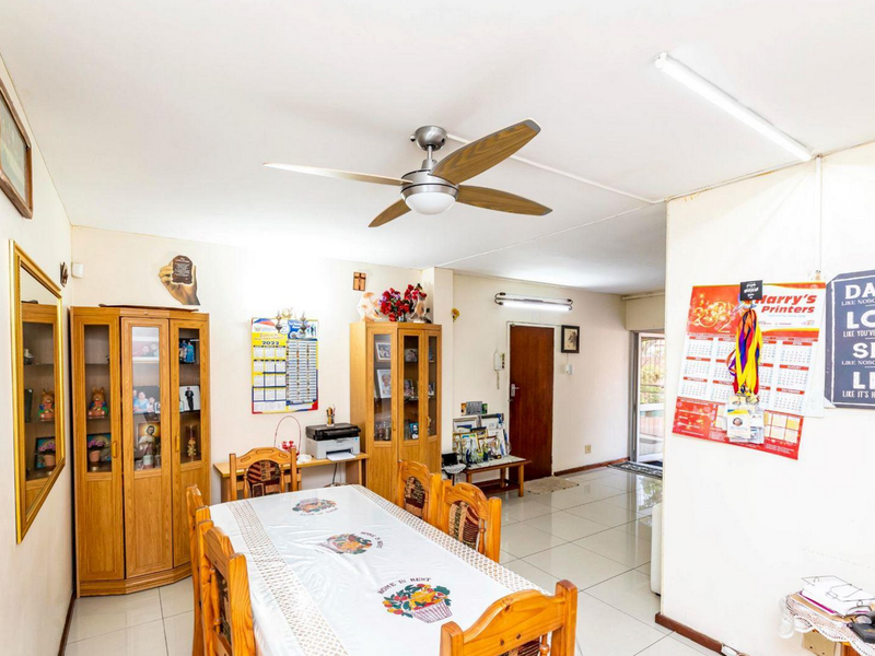A functional dining area featuring tiled flooring, a ceiling fan, and direct access to an adjacent living space.