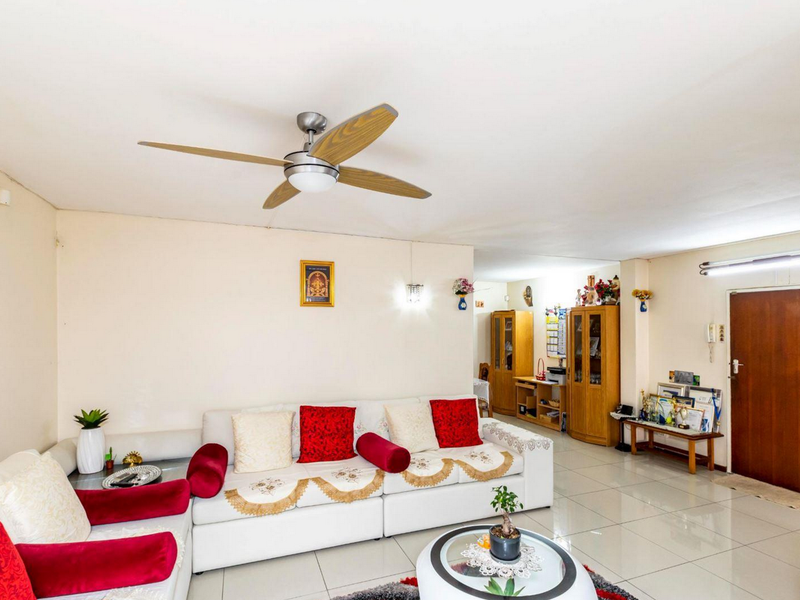 A spacious living area featuring neutral tiled flooring, a ceiling fan, and a functional layout with access to an internal door.
