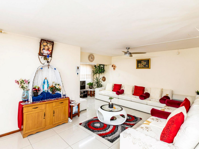 A spacious living room featuring neutral tiled flooring and a ceiling fan, offering a comfortable and functional layout for relaxation.