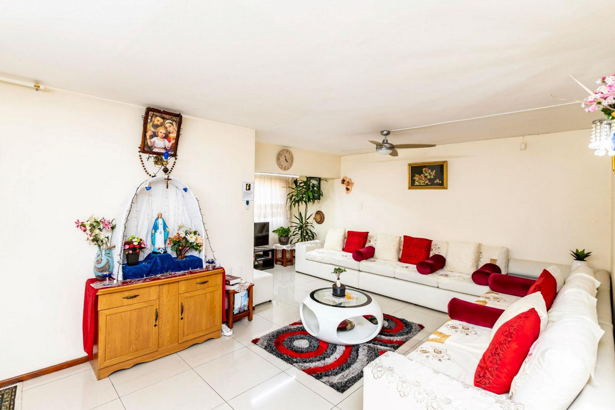 A spacious living room featuring neutral tiled flooring and a ceiling fan, offering a comfortable and functional layout for relaxation.