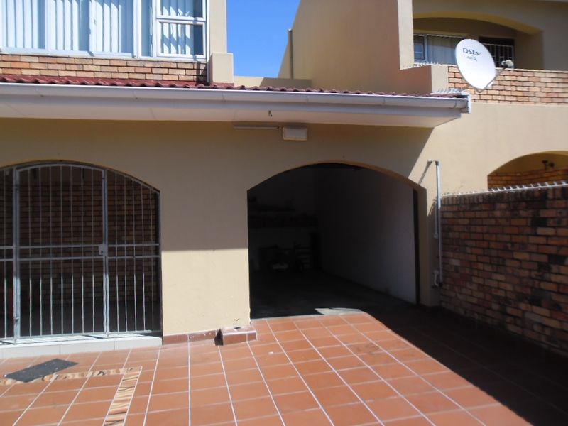 A townhouse garage entrance featuring tiled flooring, an arched opening, and a secure gated access point.