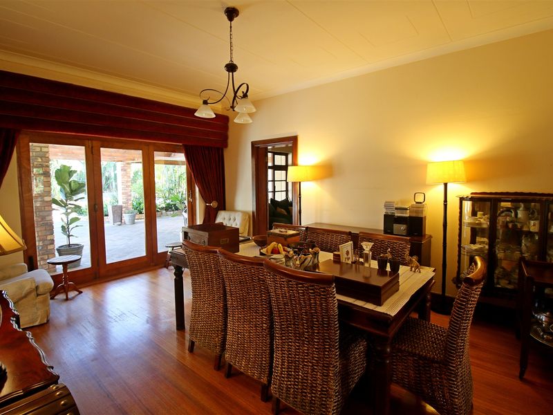 A dining room featuring warm hardwood flooring and large wooden framed glass sliding doors that provide access to the outdoor patio area.