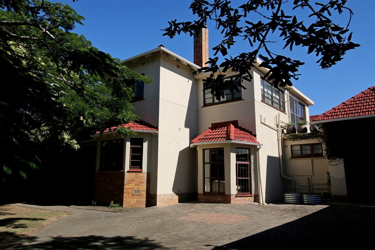 Rear view of a multi-story house featuring a paved courtyard, brick chimney, and traditional tiled roof architecture.