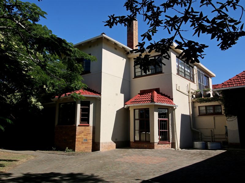 Rear view of a multi-story house featuring a paved courtyard, brick chimney, and traditional tiled roof architecture.