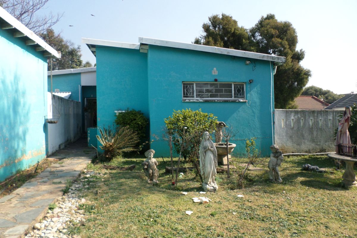 Rear exterior view of the property featuring a stone pathway, a small garden area, and a blue painted facade with a skillion roof.