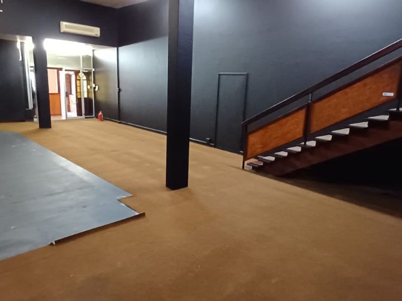 Spacious open-plan office area featuring a staircase, dark painted walls, and split-system air conditioning units.