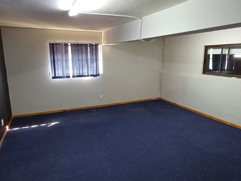 An empty office space featuring blue carpeting, split-system air conditioning, and functional window treatments, suitable for a professional workspace.