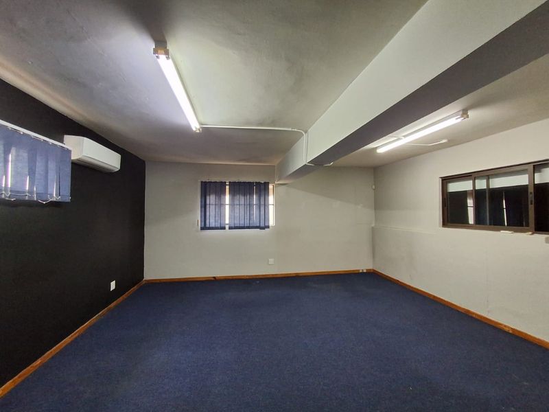 An empty office space featuring blue carpeting, split-system air conditioning, and functional fluorescent lighting, suitable for a professional workspace setup.