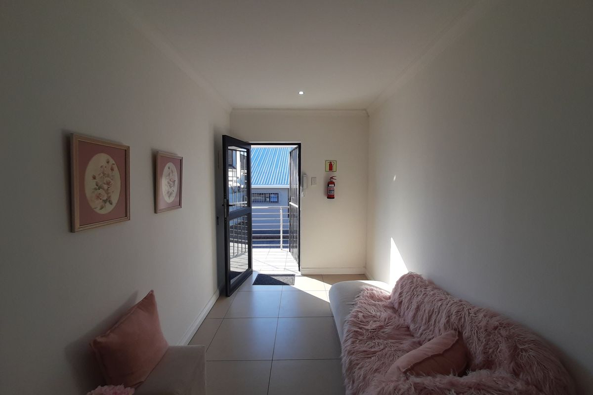A bright office space featuring tiled flooring, an intercom system, and a security gate leading to an outdoor area.