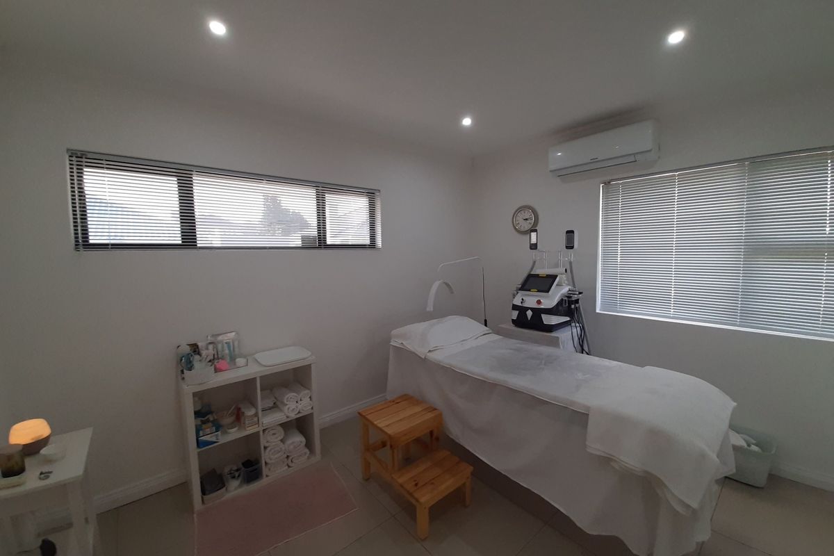 A well-maintained office or treatment room featuring tiled flooring, recessed lighting, split-system air conditioning, and horizontal blinds for adjustable natural light.