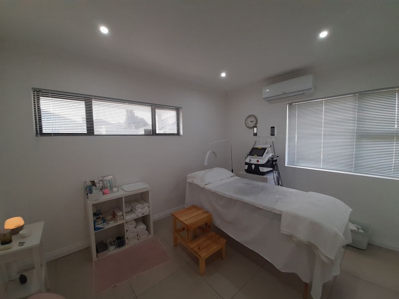 A well-maintained office or treatment room featuring tiled flooring, recessed lighting, split-system air conditioning, and horizontal blinds for adjustable natural light.
