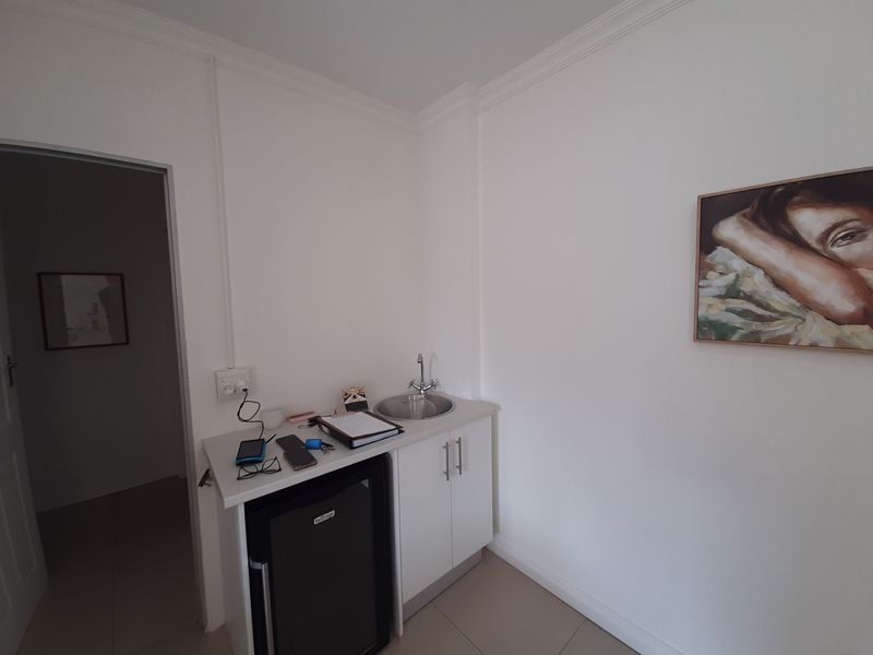 A compact utility space featuring a built-in kitchenette cabinet with a stainless steel sink and tiled flooring.