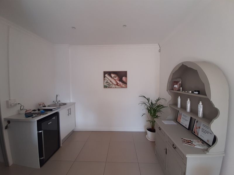 A functional office space featuring a built-in kitchenette with a sink and tiled flooring, suitable for professional use.