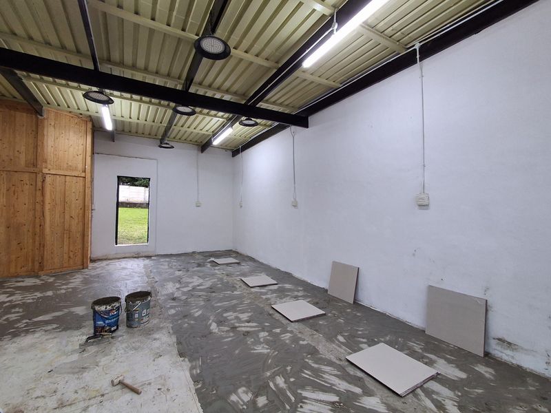 An unfinished utility space featuring exposed steel beams, corrugated metal ceiling, and basic electrical infrastructure, currently undergoing floor renovation.