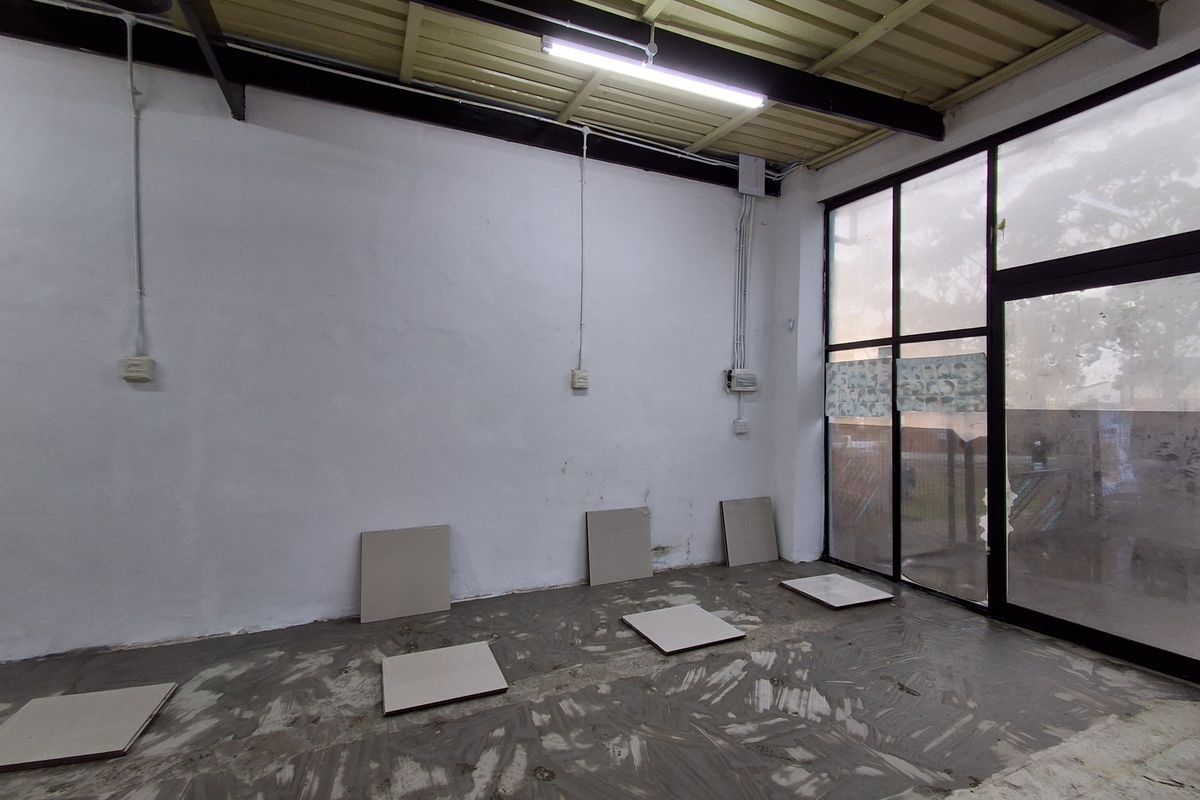An empty retail space featuring exposed steel beams, large glass storefront windows, and unfinished flooring, offering a blank canvas for commercial customization.