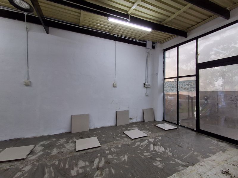 An empty retail space featuring exposed steel beams, large glass storefront windows, and unfinished flooring, offering a blank canvas for commercial customization.