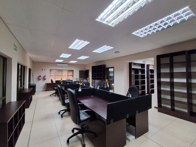 A functional office space featuring tiled flooring, recessed lighting, built-in shelving units, and an integrated air conditioning system.