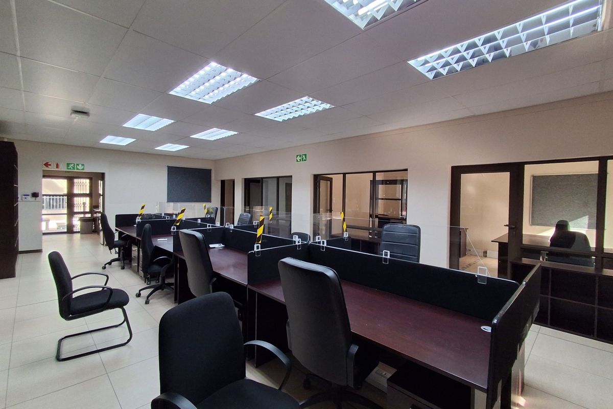 A professional open-plan office space featuring tiled flooring, suspended ceilings with recessed lighting, and integrated glass-partitioned workstations.