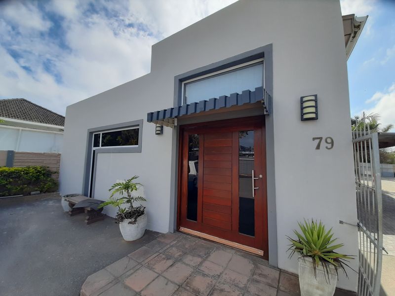 Front entrance of a commercial property featuring a solid wood door, metal awning, and paved entryway.