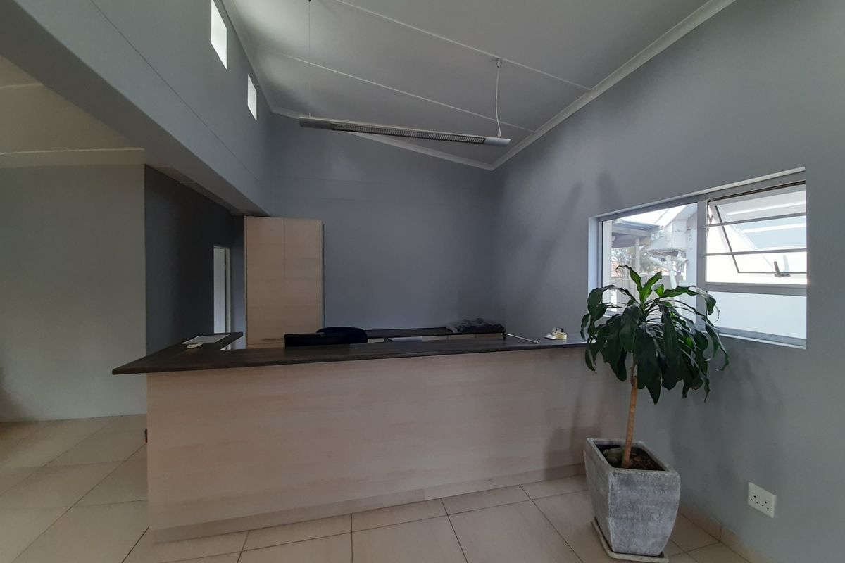 A clean, professional office space featuring a built-in reception desk, tiled flooring, and ample natural light from clerestory and louvered windows.