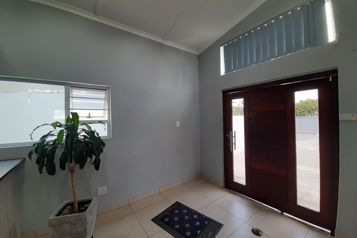 A bright and clean entrance area featuring tiled flooring, a solid timber front door with sidelights, and a high clerestory window for natural light.