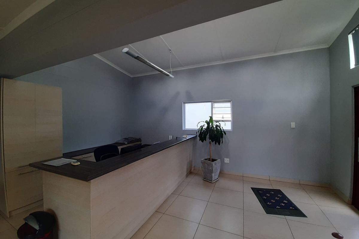 A professional office space featuring a built-in reception desk, tiled flooring, and neutral wall finishes, suitable for a commercial reception or administrative area.