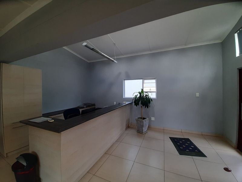 A professional office space featuring a built-in reception desk, tiled flooring, and neutral wall finishes, suitable for a commercial reception or administrative area.