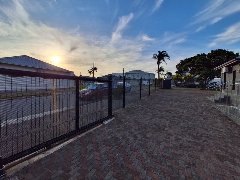 Exterior view of the office property featuring a paved driveway, secure perimeter fencing with a sliding gate, and an external staircase entrance.