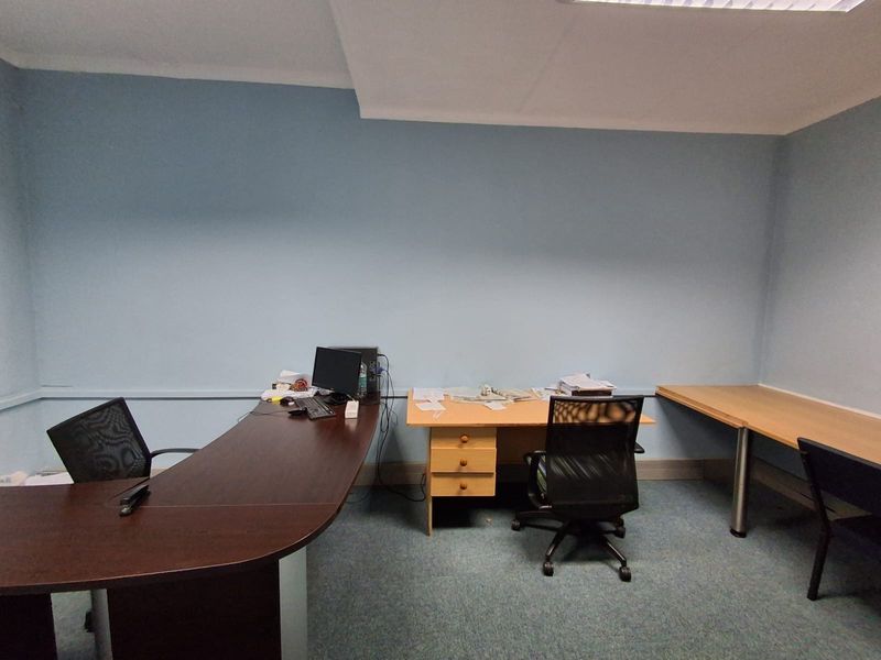 A functional office space featuring blue painted walls, carpeted flooring, and recessed ceiling lighting, suitable for a professional work environment.