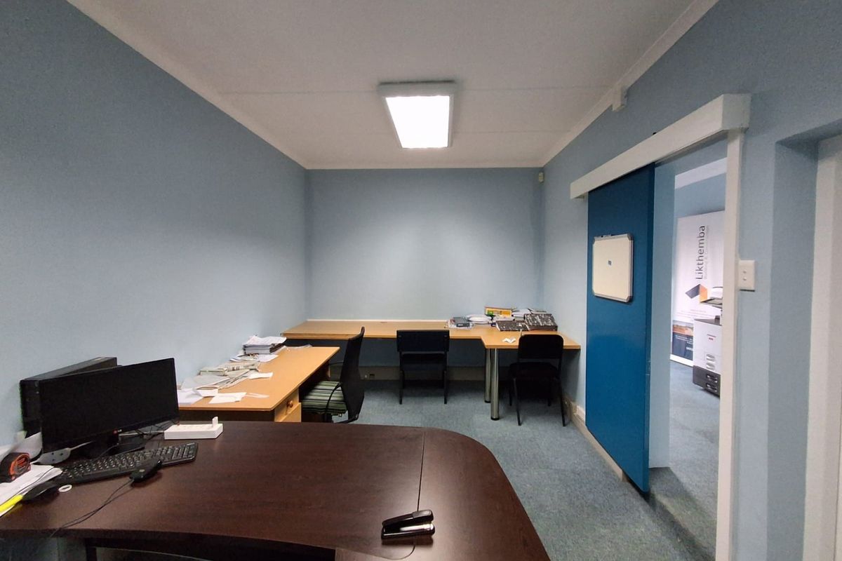 A functional office space featuring blue walls, carpeted flooring, and a sliding door, providing a practical work environment.