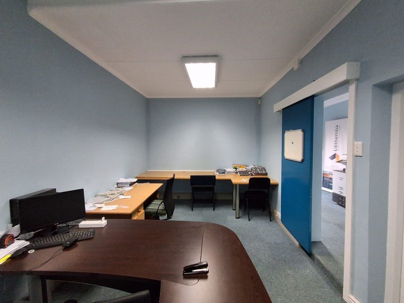 A functional office space featuring blue walls, carpeted flooring, and a sliding door, providing a practical work environment.