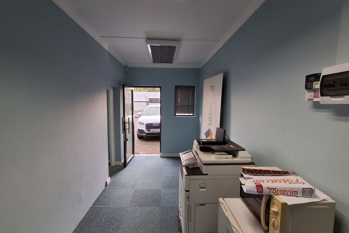 A functional office space featuring carpeted flooring, recessed ceiling lighting, integrated air conditioning, and a wall-mounted electrical distribution board.