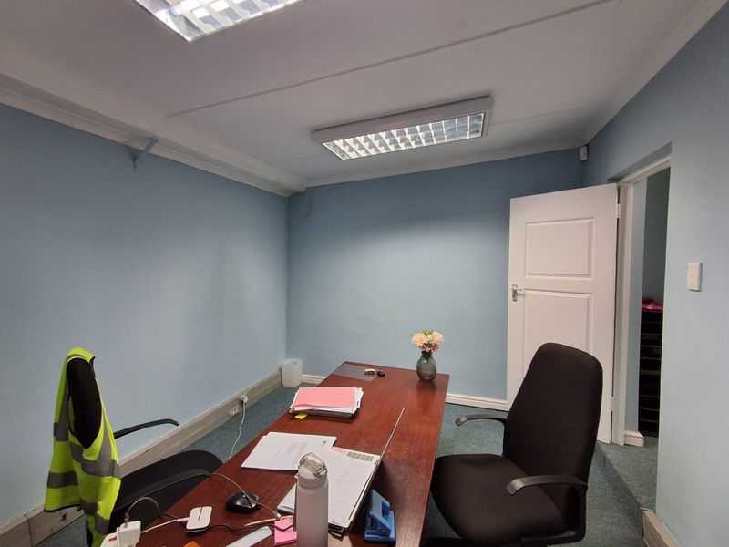 A functional office space featuring blue painted walls, carpeted flooring, and recessed ceiling lighting, providing a practical environment for professional work.