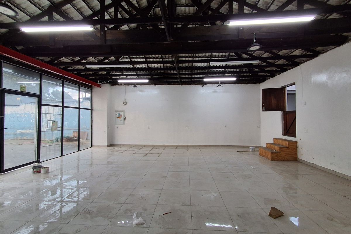 Spacious open-plan retail area featuring high exposed timber ceilings, large glass storefront windows, and durable tiled flooring, suitable for various commercial uses.