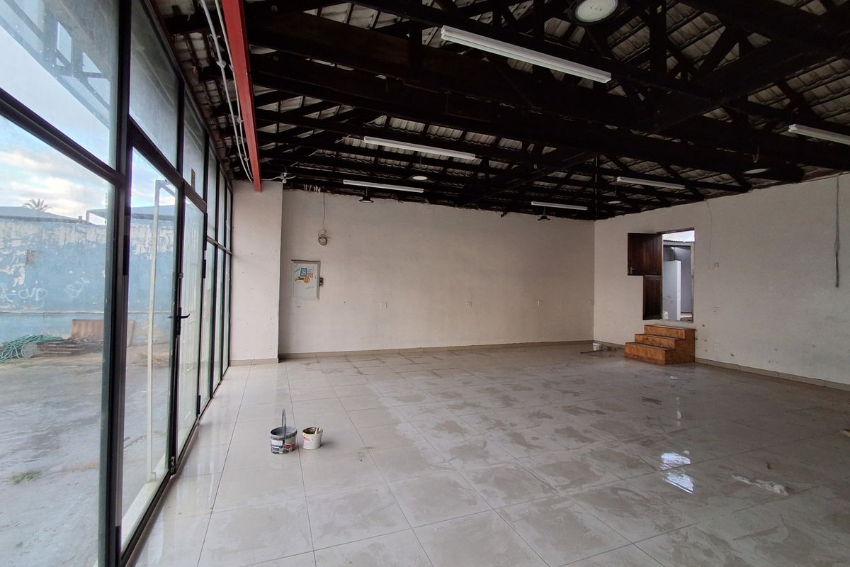 Spacious open-plan retail area featuring high exposed timber roof trusses, large glass storefront windows, and tiled flooring, offering a versatile commercial layout.