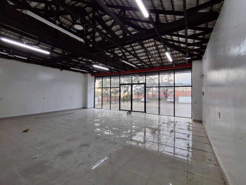 Spacious open-plan retail unit featuring high exposed timber ceilings, tiled flooring, and a large glass storefront providing excellent natural light and visibility.
