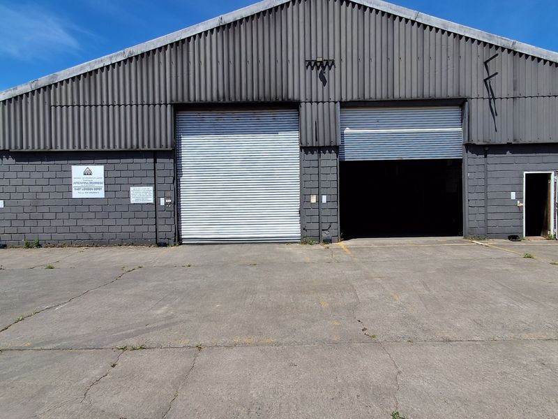 Industrial warehouse facility featuring dual roller shutter doors, masonry block construction, and a large concrete apron for vehicle access.