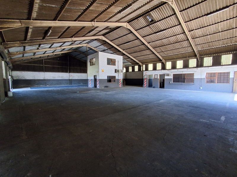 Spacious industrial warehouse featuring high-clearance steel truss roofing, concrete flooring, and an integrated internal office block with air conditioning.