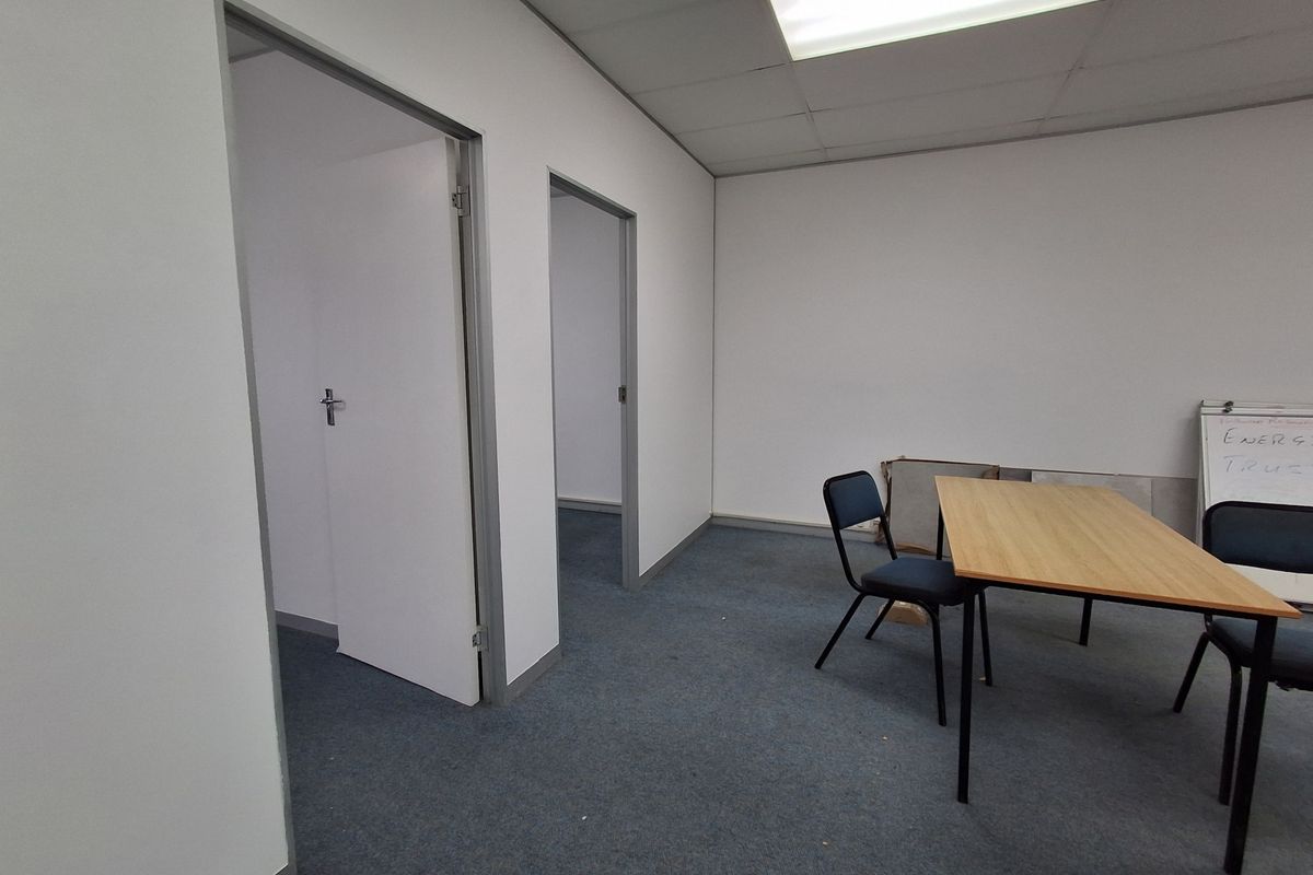 A functional office space featuring a suspended ceiling, recessed lighting, and carpeted flooring, providing a basic layout for professional use.