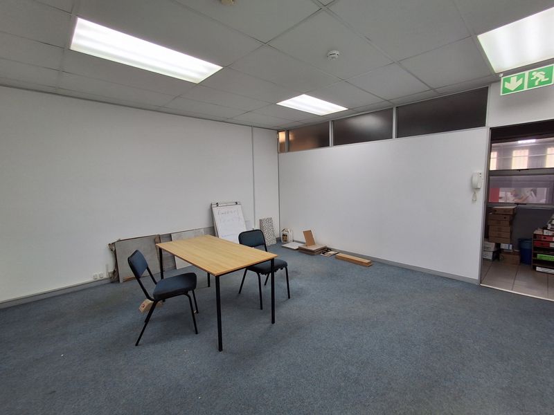 A vacant office space featuring a suspended ceiling with recessed lighting, carpeted flooring, and an intercom system, suitable for a professional workspace.