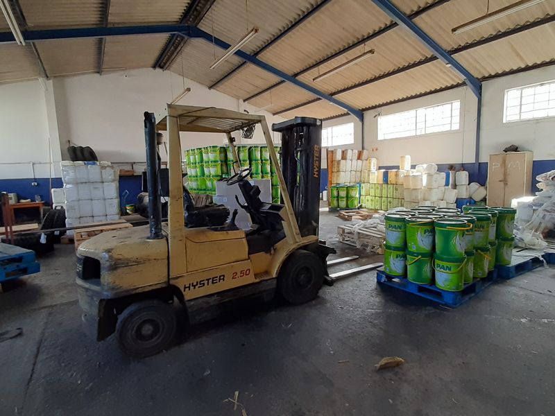 Spacious industrial utility or warehouse area featuring high ceilings with exposed steel trusses, concrete flooring, and natural light from high-level windows.