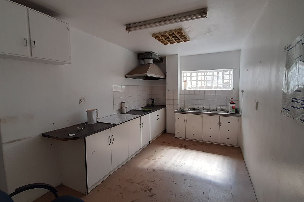 A functional kitchen area featuring built-in cabinetry, a stainless steel sink, and an extractor fan, requiring cosmetic updates to improve its overall condition.