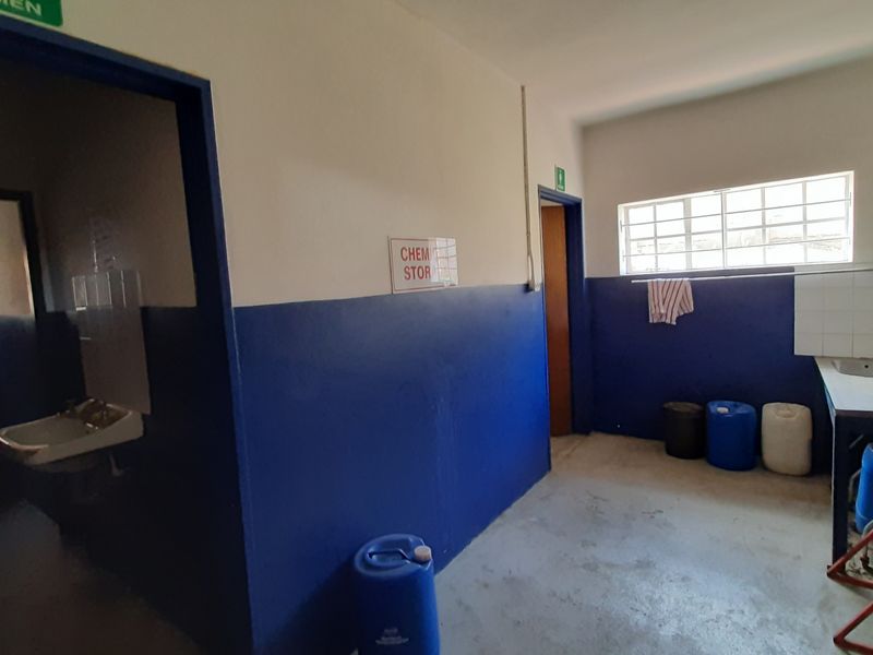 A functional utility or storage area featuring a built-in sink, tiled splashback, and direct access to an adjacent restroom facility.